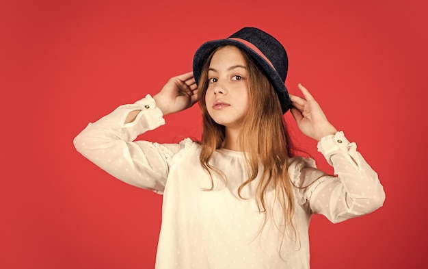 Happy small kid retro hat vintage fashion look summer accessory collection child long hair beauty and style happy childhood Young and carefree retro girl red background