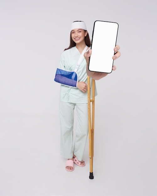 Happy smile asian woman patient put on a cast showing smartphone mockup of blank screen