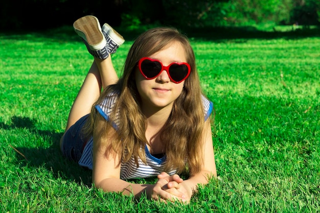 Happy smile beautiful and young girl spanding time in city park Red hearts sunglasses