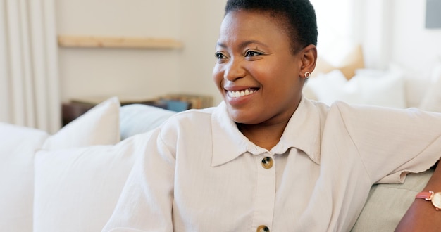 Happy smile and black woman relaxing on a sofa while watching tv in the living room of her modern house Happiness laughing and African lady streaming a movie while sitting on a couch in her lounge