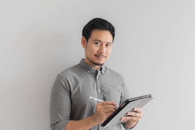 Happy and smile entrepreneur businessman work on his tablet with grey background.