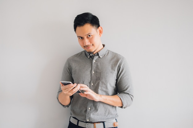 Happy smile face of handsome Asian man use smartphone stand isolated on gray background