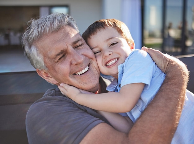 Happy smile and grandfather hugging his grandchild while playing together at the family home Happiness playful and elderly man in retirement embracing and bonding with his toddler grandson