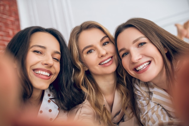 Happy smiles. Three girls making selfie and looking happy