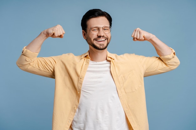 Photo happy smiling bearded man showing muscles posing on blue background