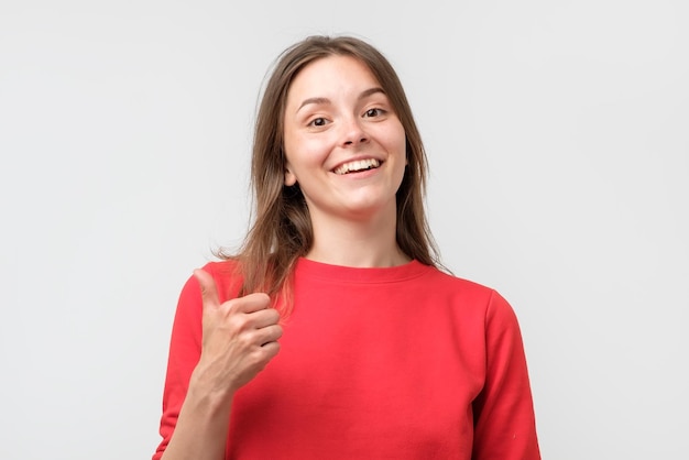 Happy smiling beautiful young woman showing thumbs up gesture