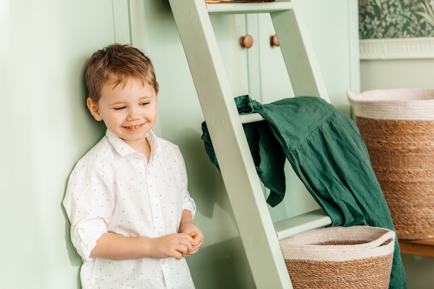 Happy smiling blond child stands at home.