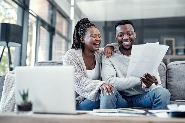 Happy smiling and carefree black couple checking their finances on a laptop at home Cheerful husband and wife excited about their financial freedom savings investment and future planning