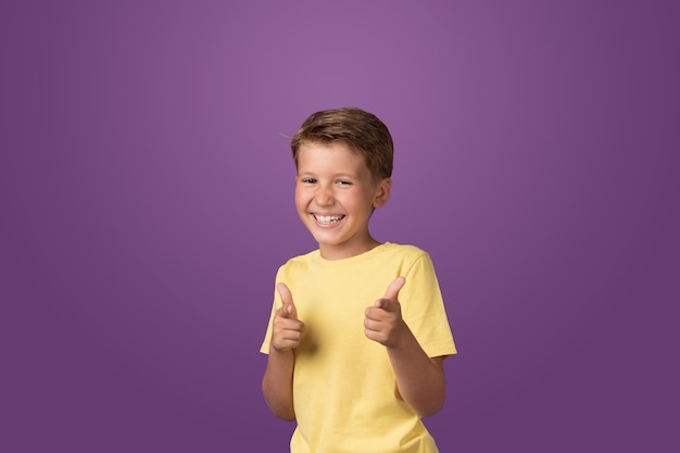 Happy smiling Caucasian preteen boy posing looking to the camera against purple background