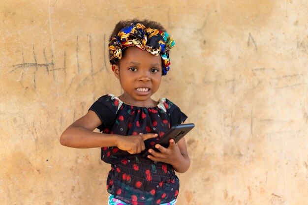 Happy smiling child girl watching in her mobile phone outdoors in summer