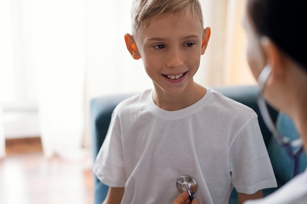 Happy smiling child patient at usual medical inspection. Doctor and kid boy at home. Medicine, healthcare concepts.