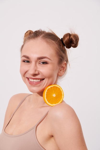 Happy smiling clean skin woman holding orange near the face