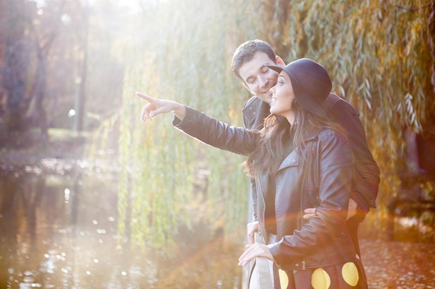 Happy smiling couple walking in autumn park near a lake