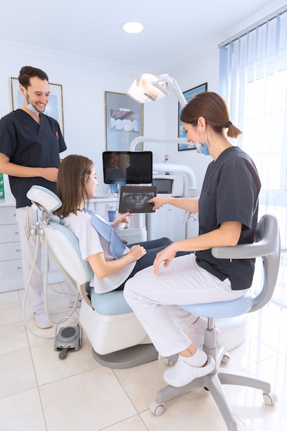 Happy smiling dentist showing dental x-ray to female patient