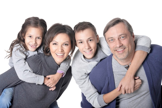 Happy smiling family of four posing together on white