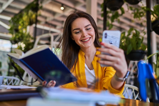 Happy smiling female worker speaking video call in office with mobile phone.