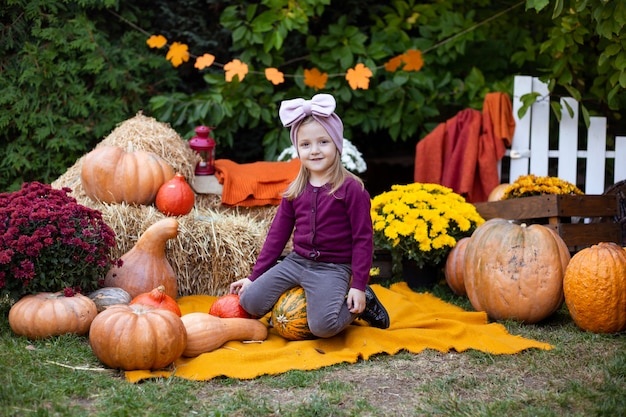 Happy smiling girl sitting on pumpkin in autumn background