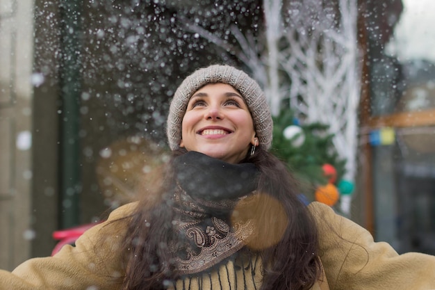 Happy smiling girl under snow in winter for holidays