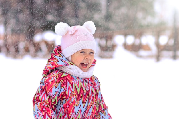 Happy and smiling little girl laughing looking at snow in winter snowy park