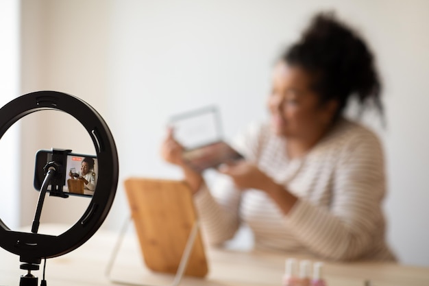 Happy smiling makeup artist blogger recording video while applying makeup