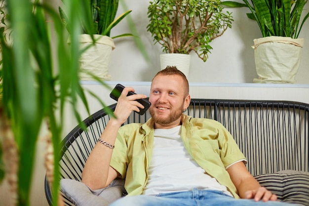 Happy smiling man holding mobile phone speaking talking with friends or family using loudspeake