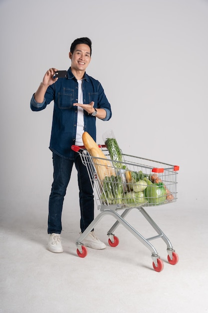 Happy smiling man pushing supermarket cart isolated on white background