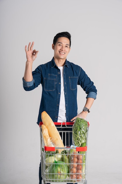 Happy smiling man pushing supermarket cart isolated on white background