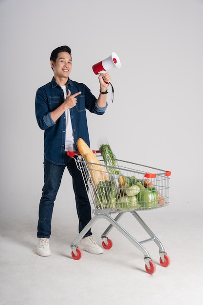 Happy smiling man pushing supermarket cart isolated on white background