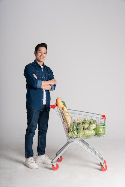 Happy smiling man pushing supermarket cart isolated on white background