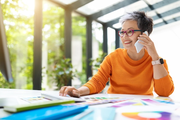 Happy smiling mature woman designer working at green office