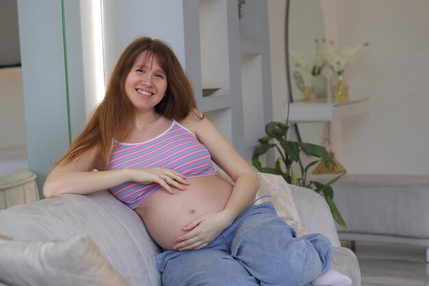 Happy smiling pregnant woman looking camera by touching or feeling tummy concept of expecting mother