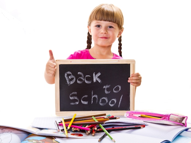 Happy smiling schoolchild holding small blackboard with text "back to school"