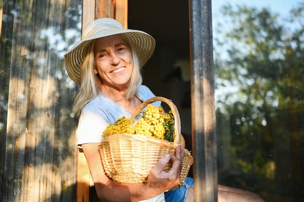 Happy smiling senior woman posing with flowers