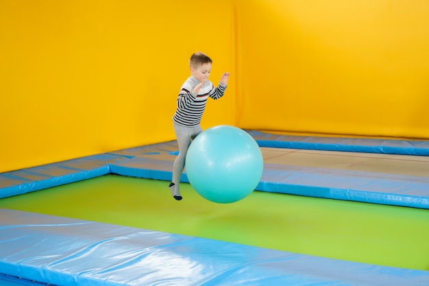 Happy smiling small kids jumping on indoors trampoline in entertainment center