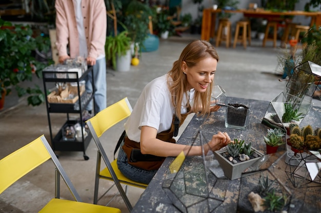 Happy smiling woman florist making succulent plant composition