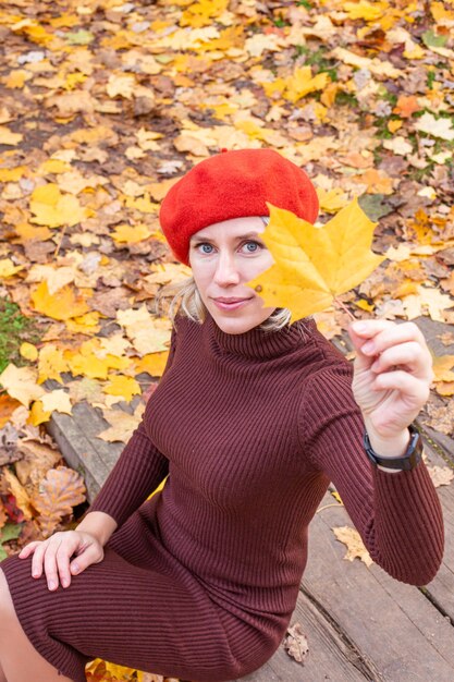 Happy smiling woman holding in her hands yellow maple leaves