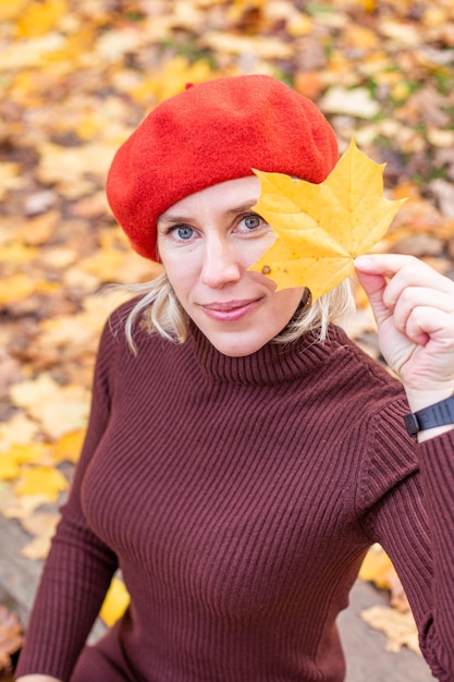 Happy smiling woman holding in her hands yellow maple leaves