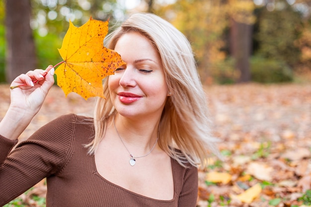 Happy smiling woman holding in her hands yellow maple leaves