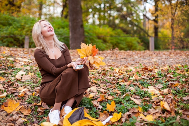 Happy smiling woman holding in her hands yellow maple leaves