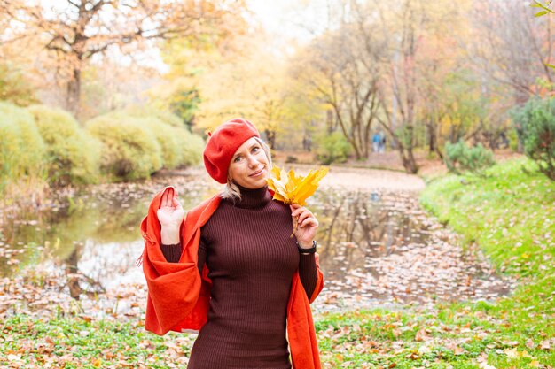 Happy smiling woman holding in her hands yellow maple leaves