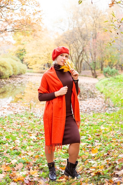 Happy smiling woman holding in her hands yellow maple leaves