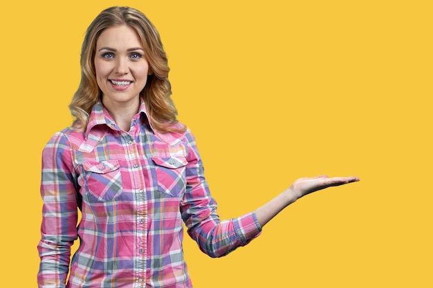 Happy smiling woman showing something with hand on color background Promotion concept