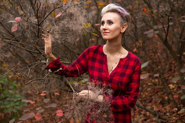 Happy smiling woman with short hair in autumn forest background