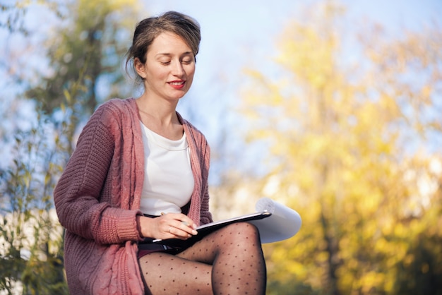 Happy smiling woman working with papers and writing letters