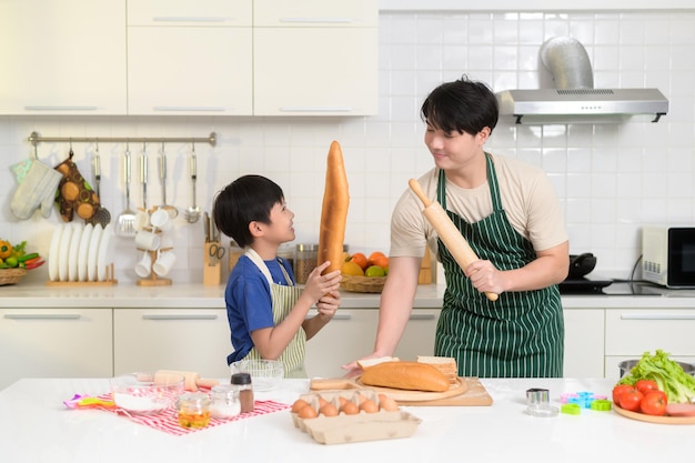 Happy smiling Young Asian father and son cooking in kitchen at home