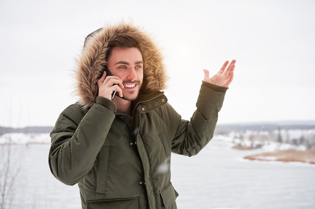 Happy smiling young caucasian man Talking on the phone Winter