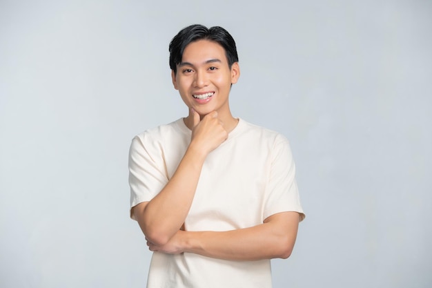 Happy smiling young handsome Asian man face with hand touching chin