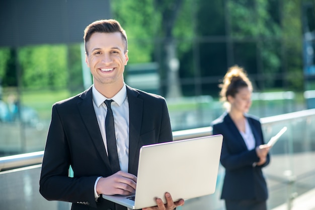 Happy smiling young man with laptop outdoors