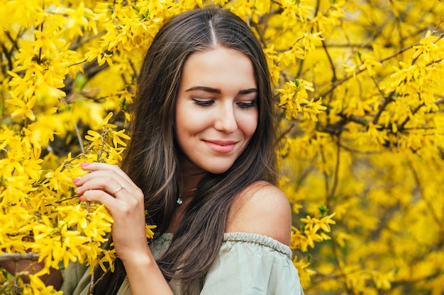 Happy smiling young woman with spring flowers at garden