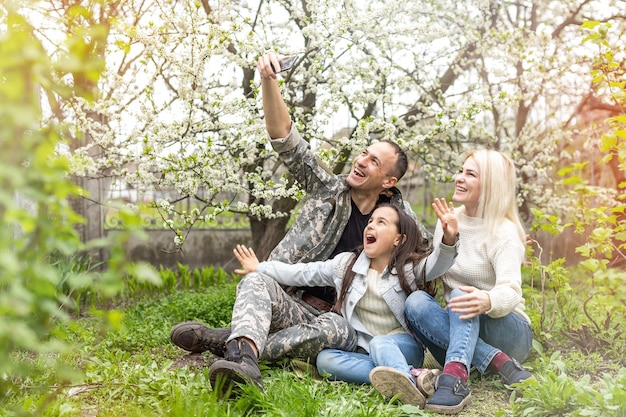 Happy soldier with family in park.